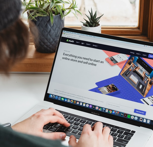 person using macbook pro on white table