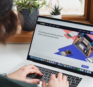 person using macbook pro on white table