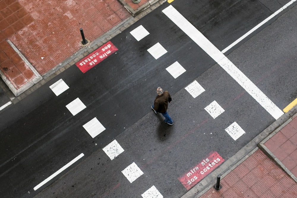woman in blue jacket walking on pedestrian lane during daytime