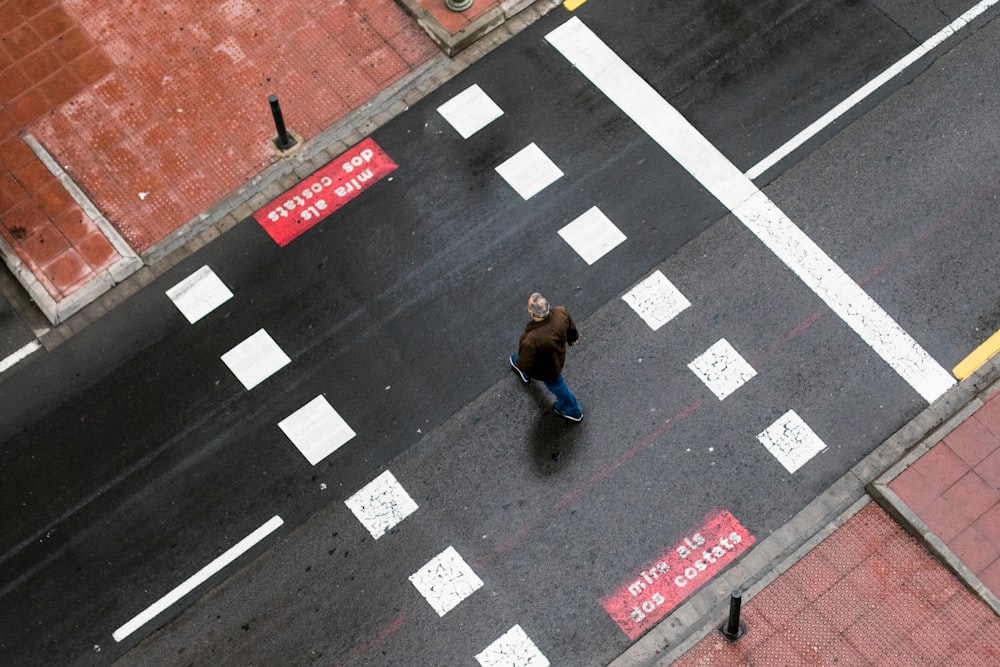 woman in blue jacket walking on pedestrian lane during daytime