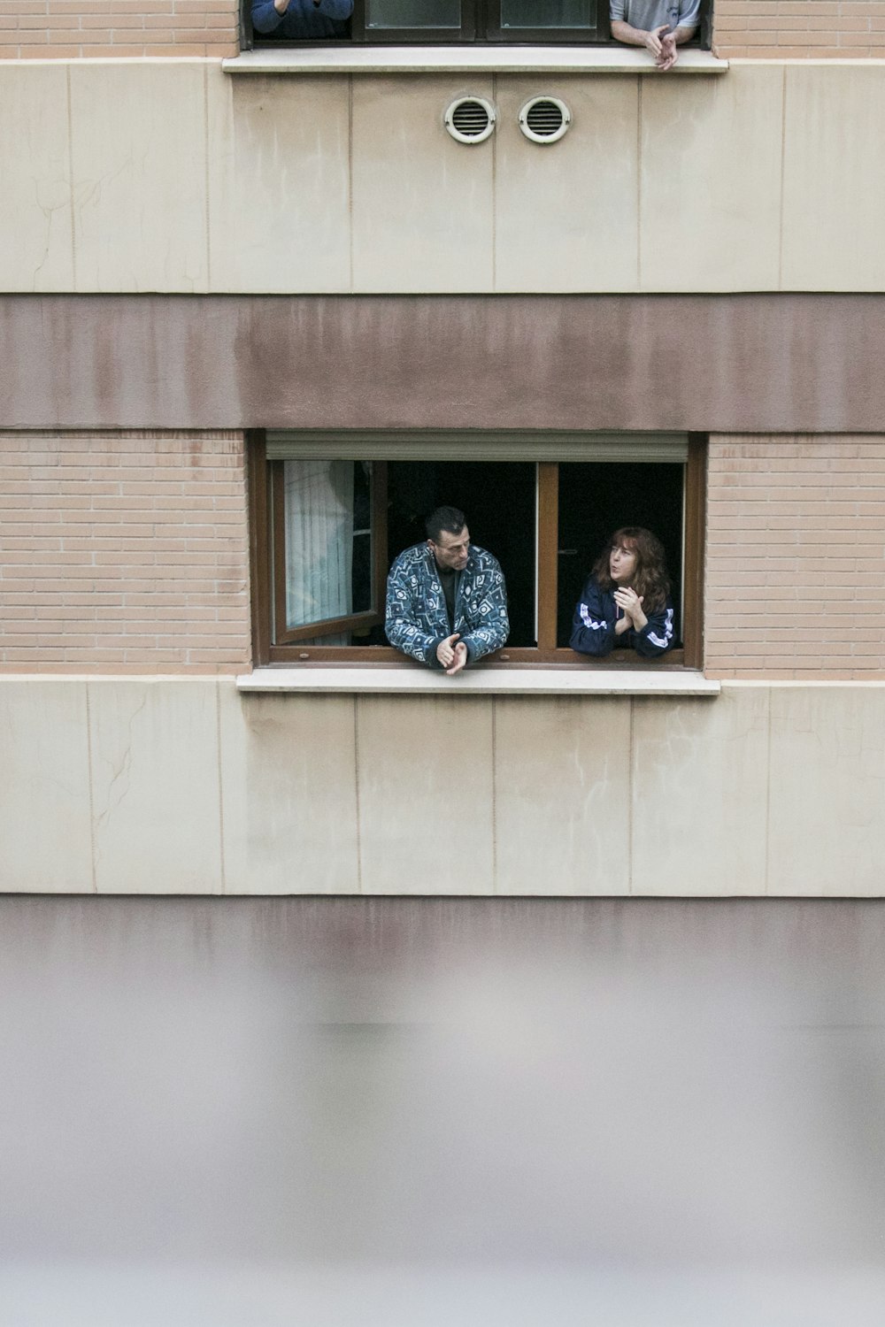 2 women and man sitting on window