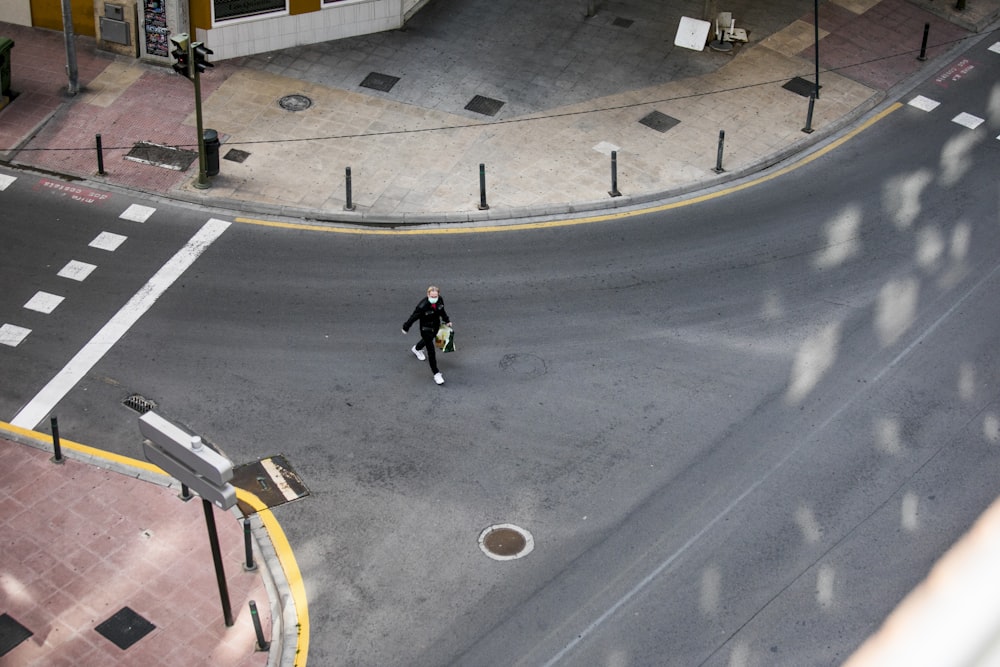 man in black jacket and black pants walking on sidewalk during daytime