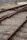 Railway tracks converge and diverge, surrounded by gravel and wooden sleepers. A metal signal or switch device is visible in the background, with a fence bordering the area.
