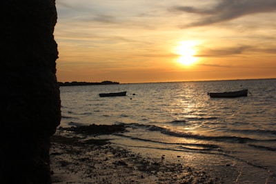 Golden sunset over the ocean with silhouettes of boats gently floating near the shore