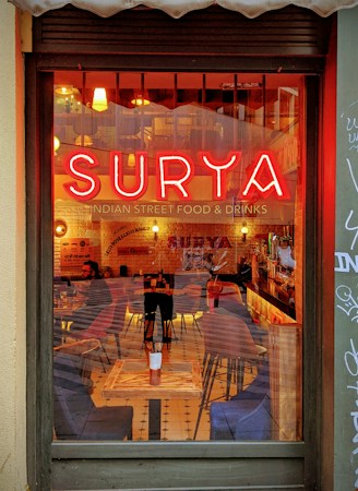 A warm and inviting view of a cozy restaurant interior with a prominent neon sign reading 