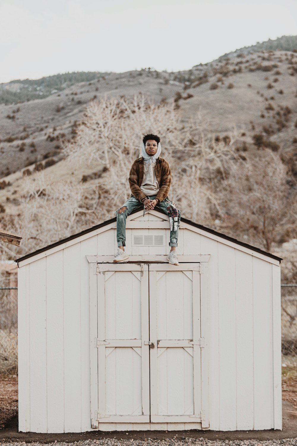 man in black and brown jacket standing beside white wooden door during daytime