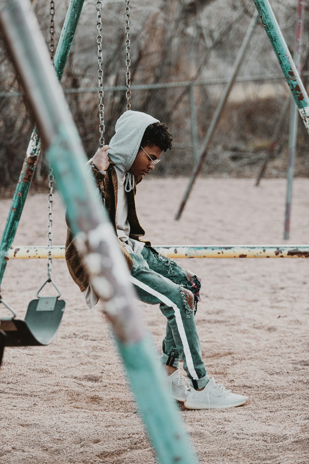 man in black t-shirt sitting on swing during daytime