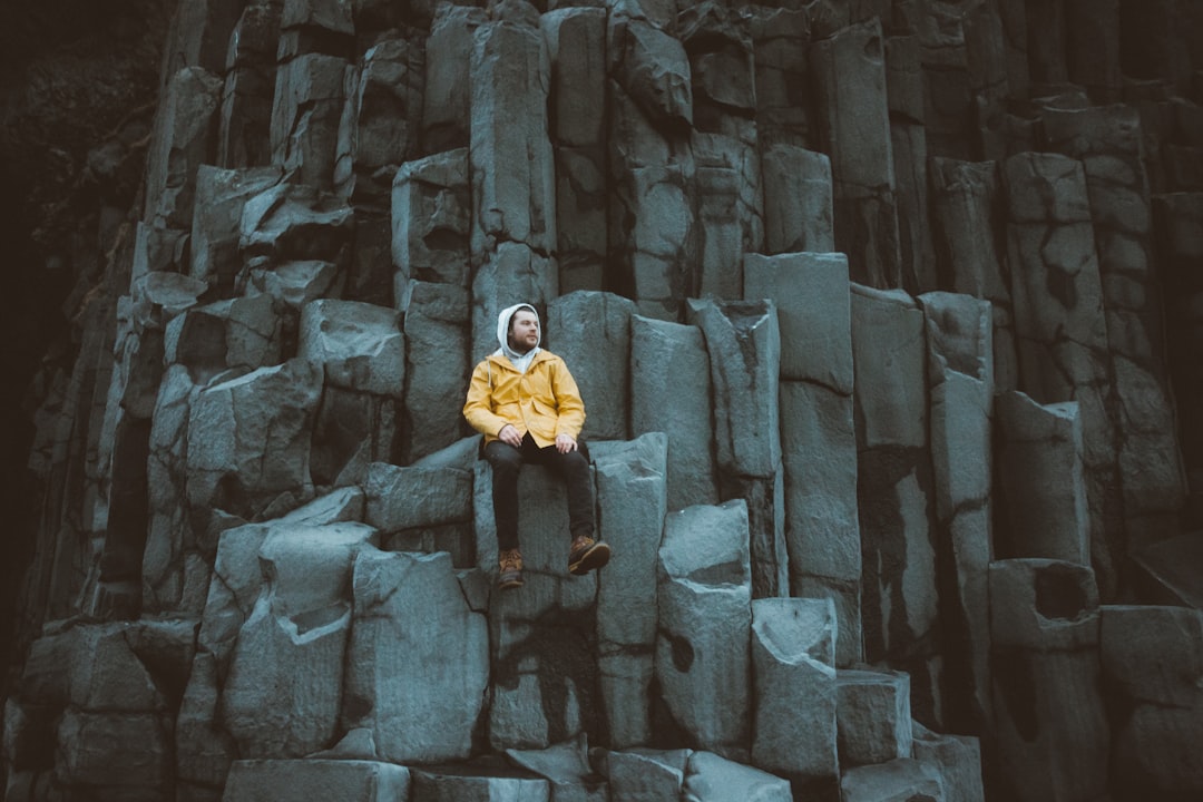 woman in yellow jacket and black pants standing on gray concrete stairs