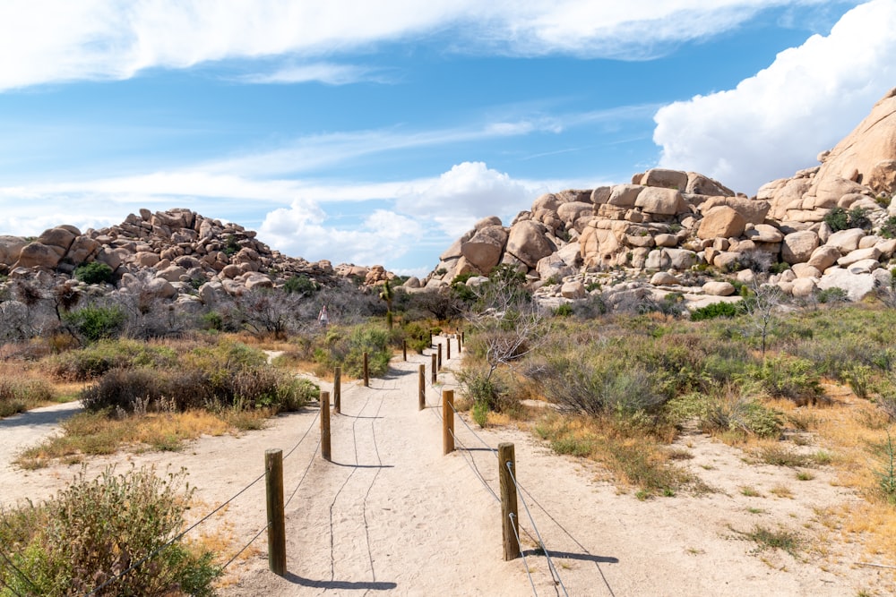 brown metal fence on brown rocky mountain under blue and white cloudy sky during daytime