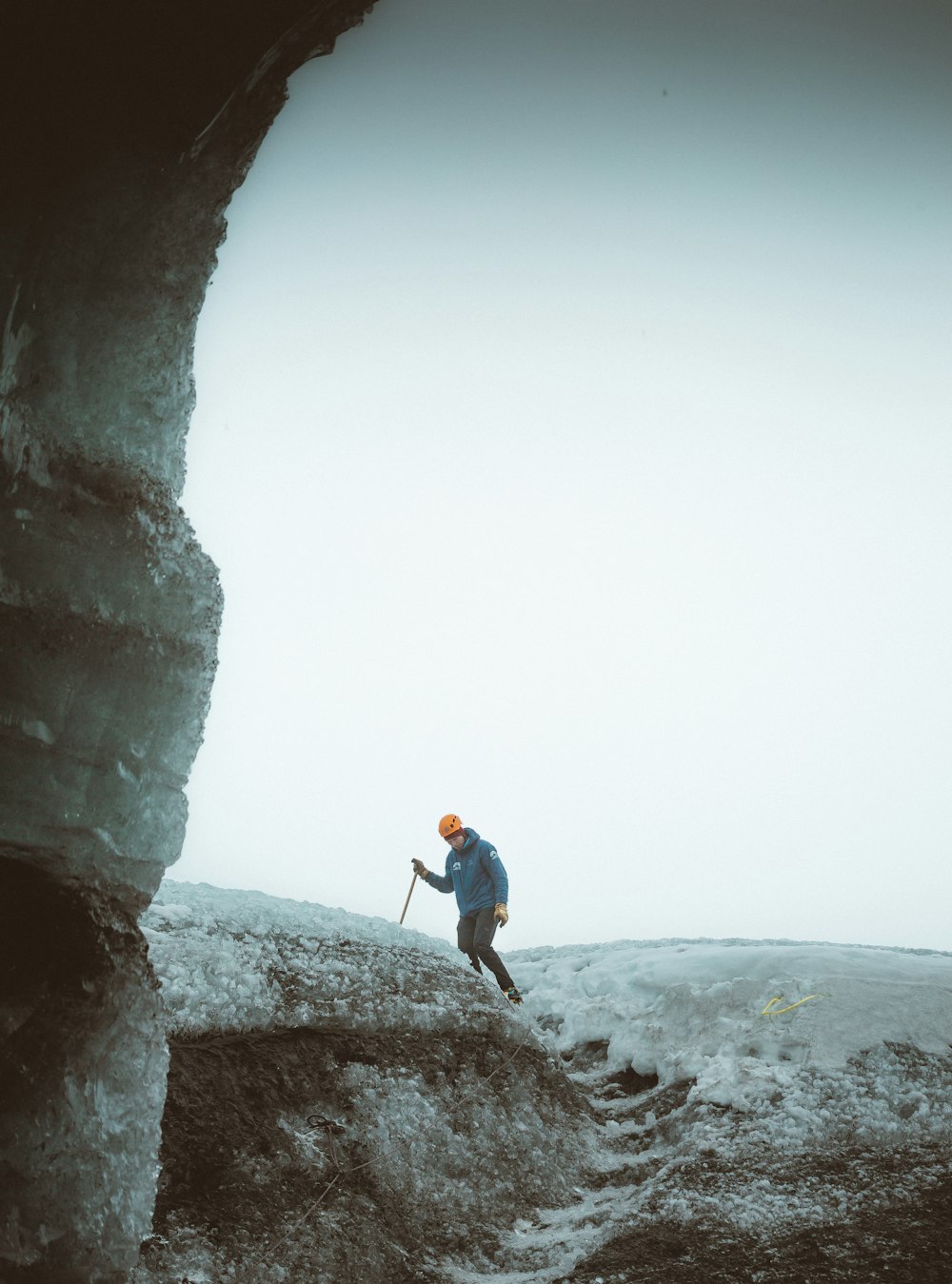 man in blue jacket and blue denim jeans standing on rock formation during daytime