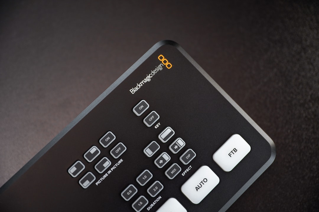 black remote control on brown wooden table, Blackmagic Designs much sought-after ATEM Mini Switcher. Available now in limited quantities at Voice & Video Sales.