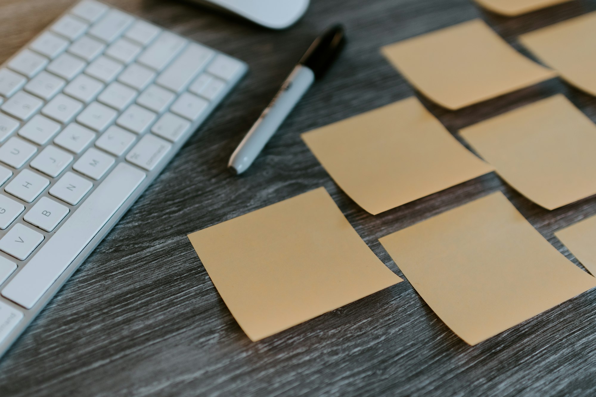 Group of blank sticky notes on a desk with a sharpie marker