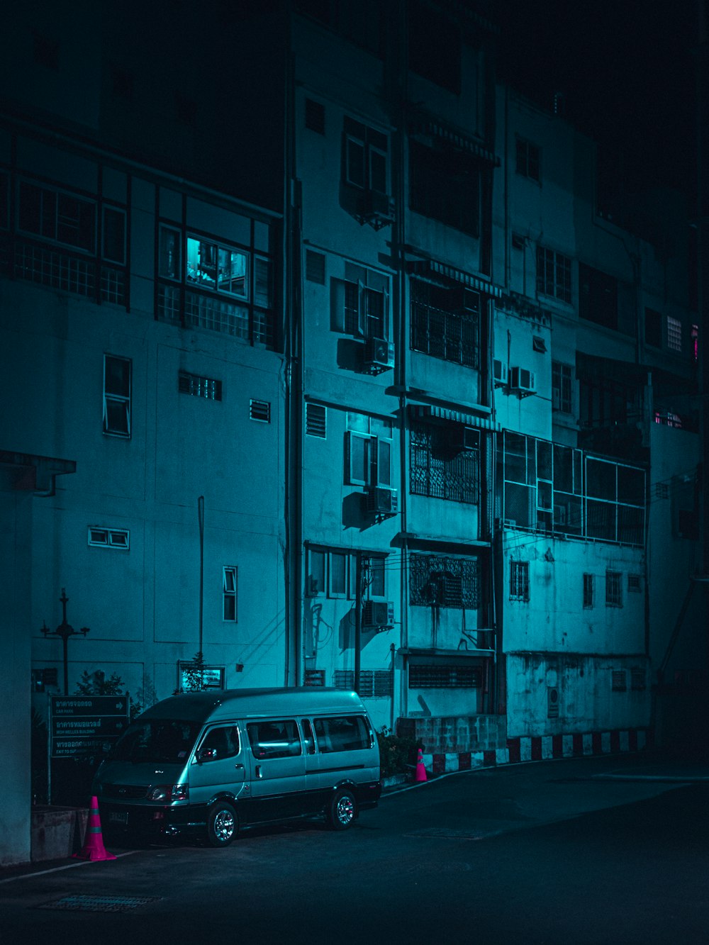 van branca estacionada ao lado do edifício de concreto azul durante o dia