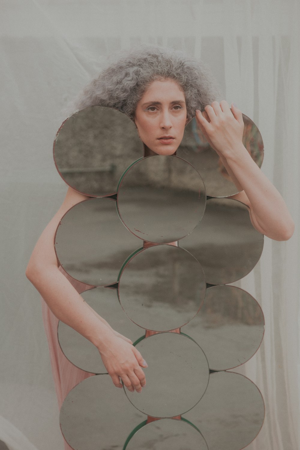 woman in pink tank top holding round mirror