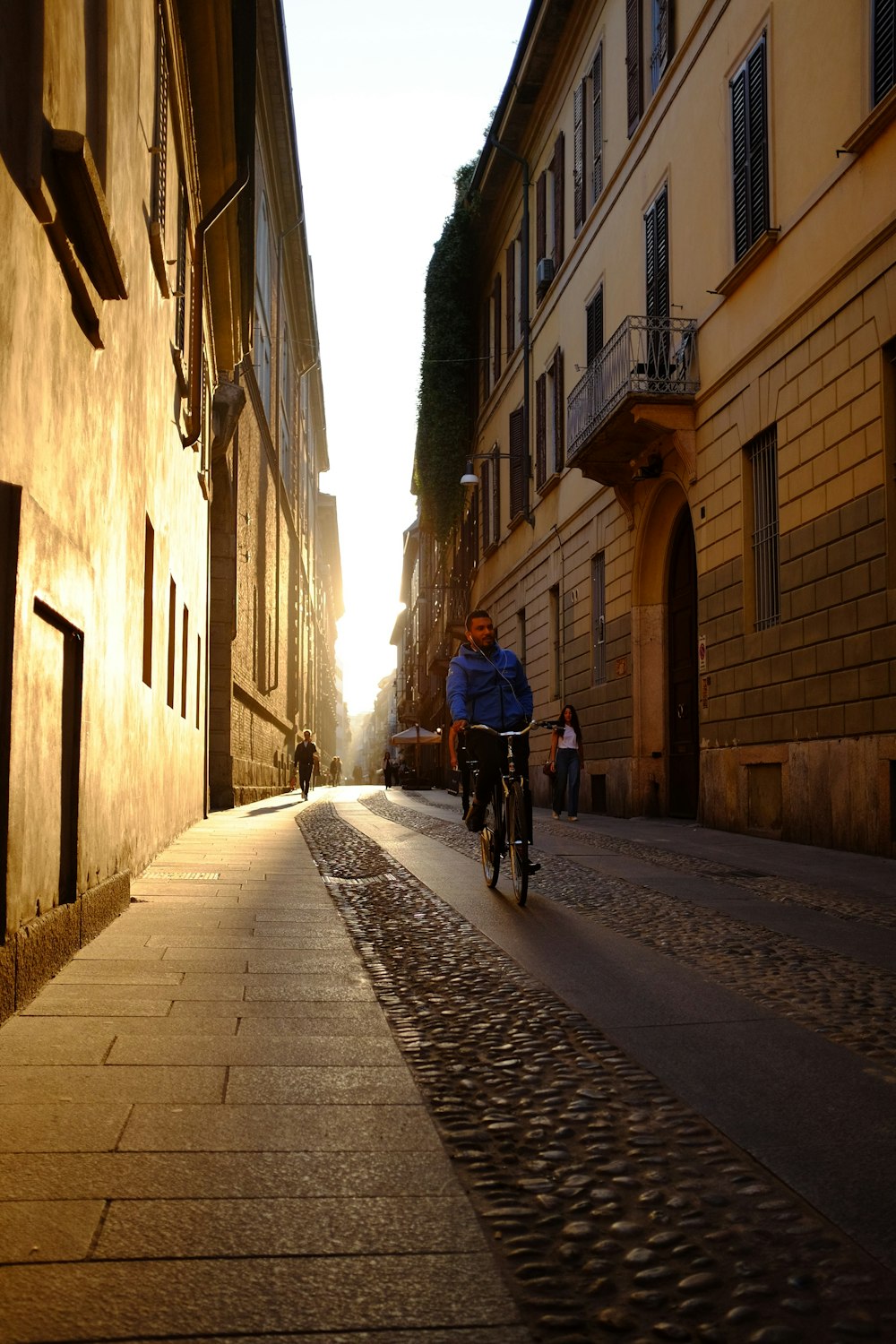 man in blue shirt riding bicycle on gray concrete road during daytime