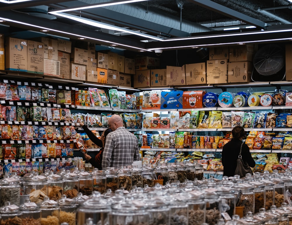 man in blue and white plaid dress shirt standing in front of food display