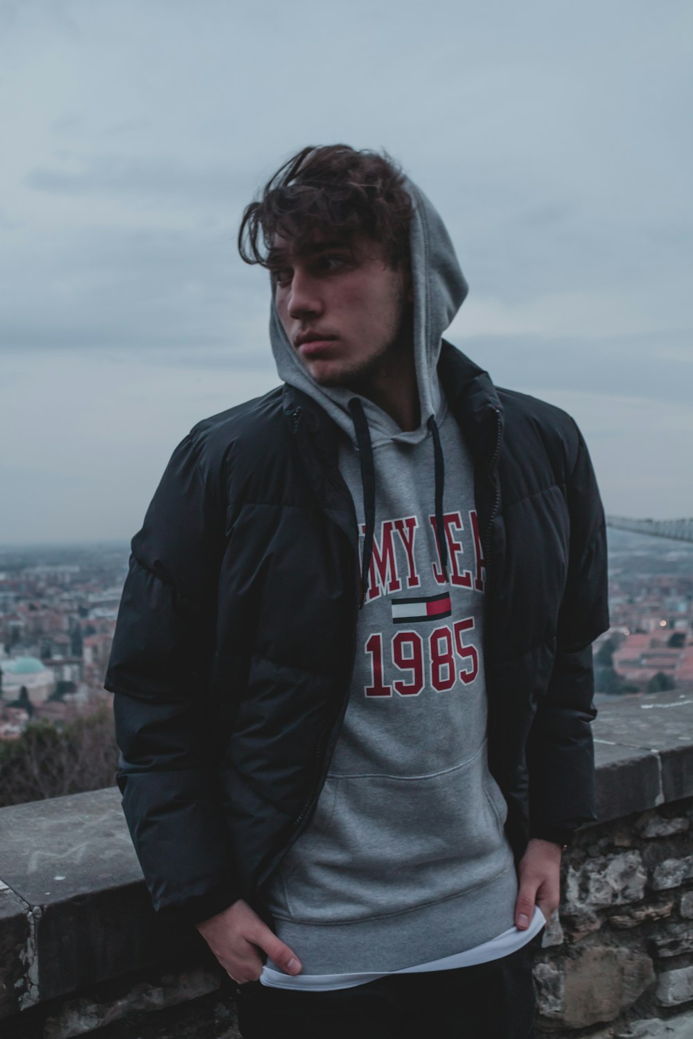 man in black and red hoodie standing on gray concrete pavement during daytime