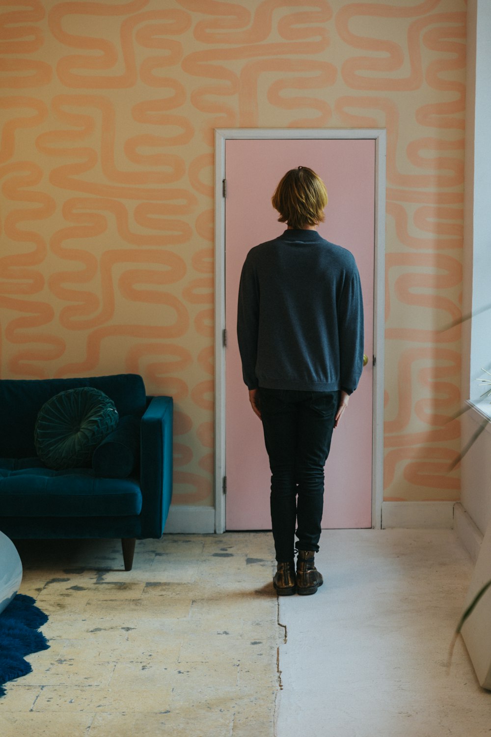 woman in gray long sleeve shirt and black pants standing near blue sofa