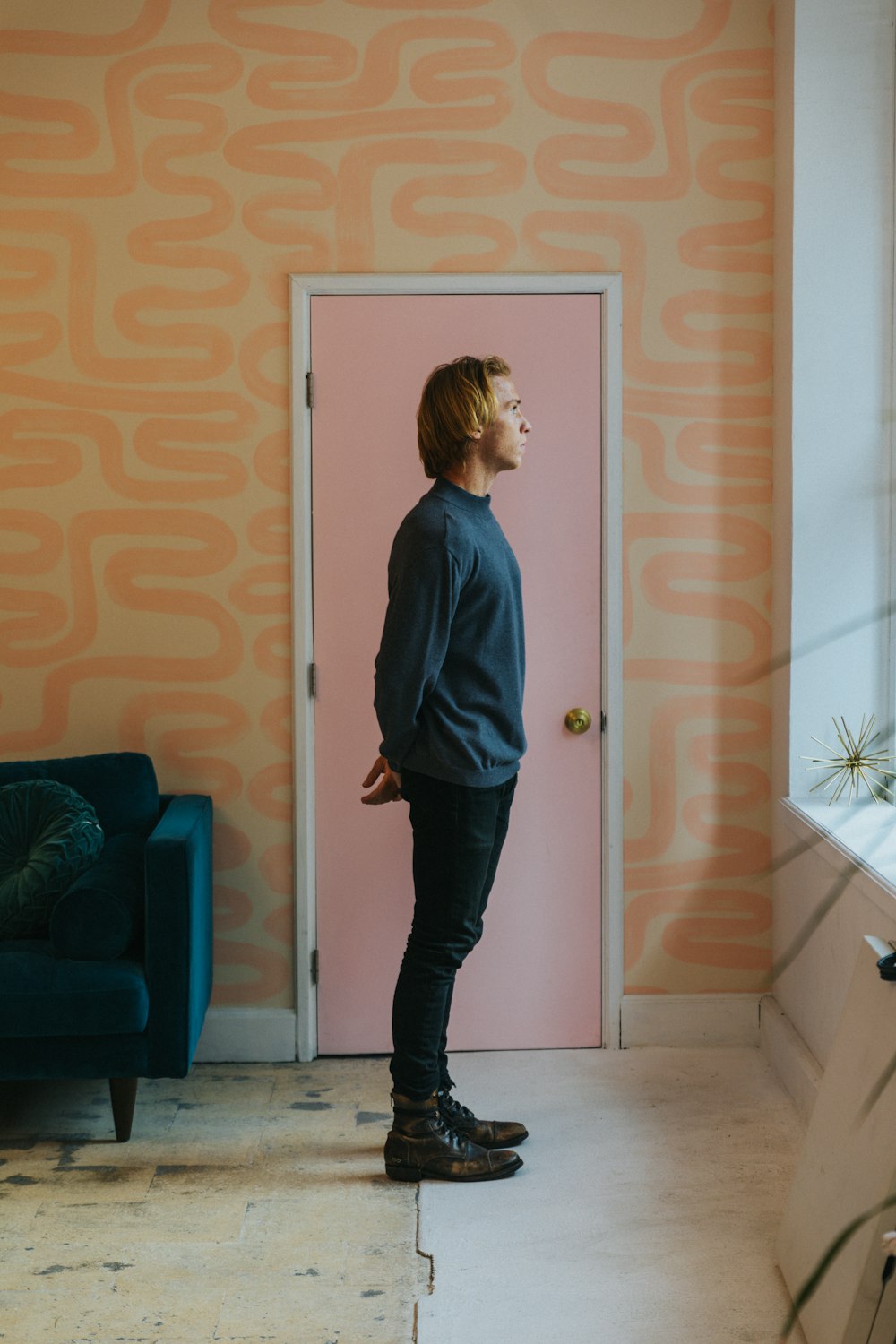 girl in blue long sleeve shirt and black pants standing beside white wooden door