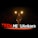 A speaker is on stage at a TEDx event, with large illuminated letters spelling out TEDxMETUAnkara behind him. The stage is dimly lit with spotlights above the speaker, creating a professional and engaging atmosphere.