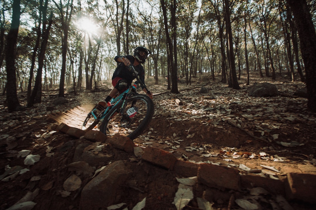 man riding on red and black motocross dirt bike on brown rocky road during daytime