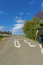A group of fathers walking together on a peaceful country path under a soft blue sky.