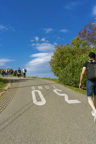 A group of fathers walking together on a peaceful country path under a soft blue sky.
