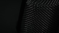 Mesh-like material with a textured, crisscross pattern covering the surface, illuminated by low light which highlights the intricate details of the weave.