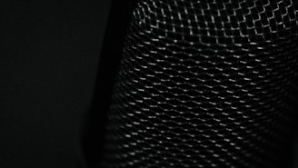 Mesh-like material with a textured, crisscross pattern covering the surface, illuminated by low light which highlights the intricate details of the weave.