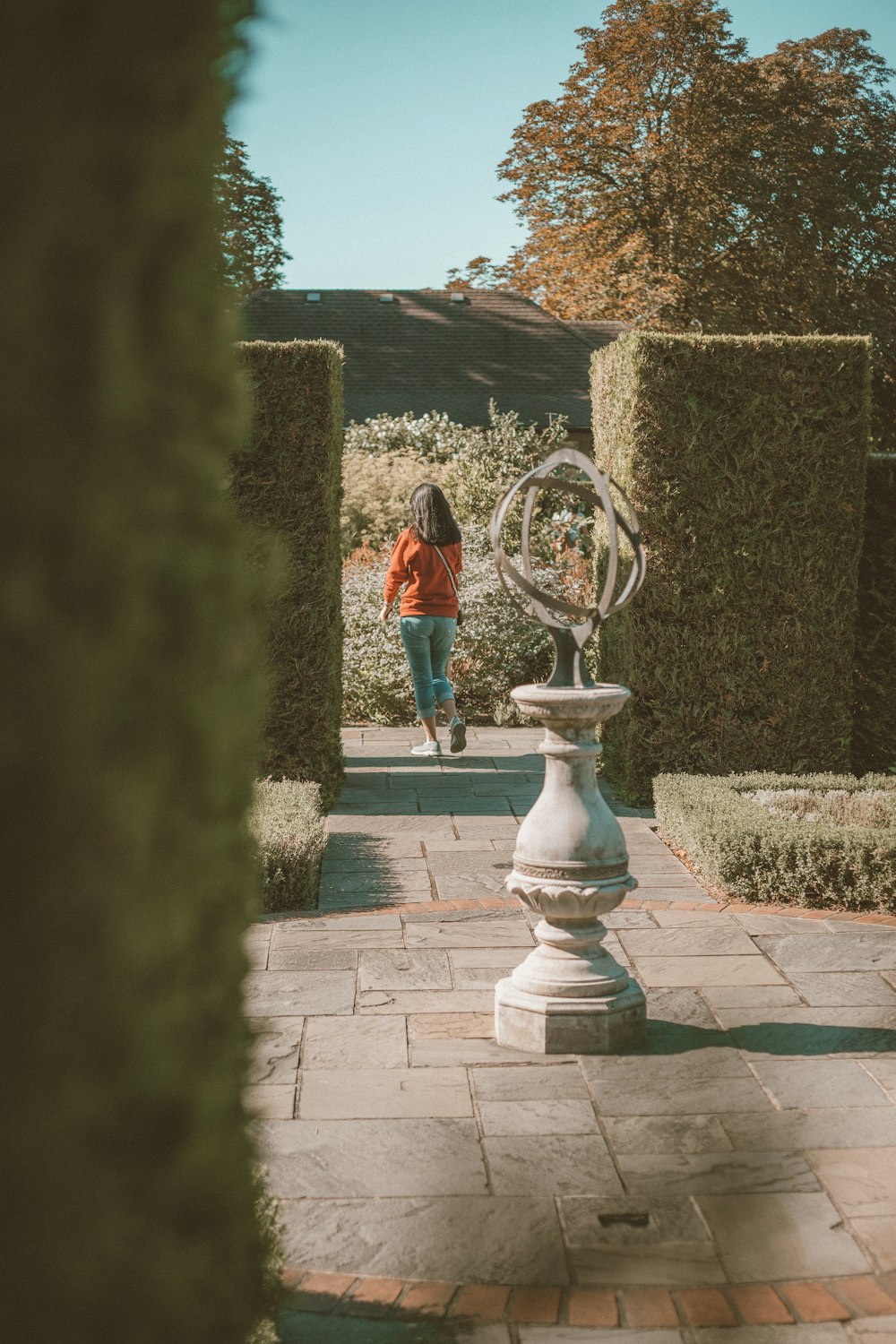 woman in red dress standing on gray concrete fountain during daytime