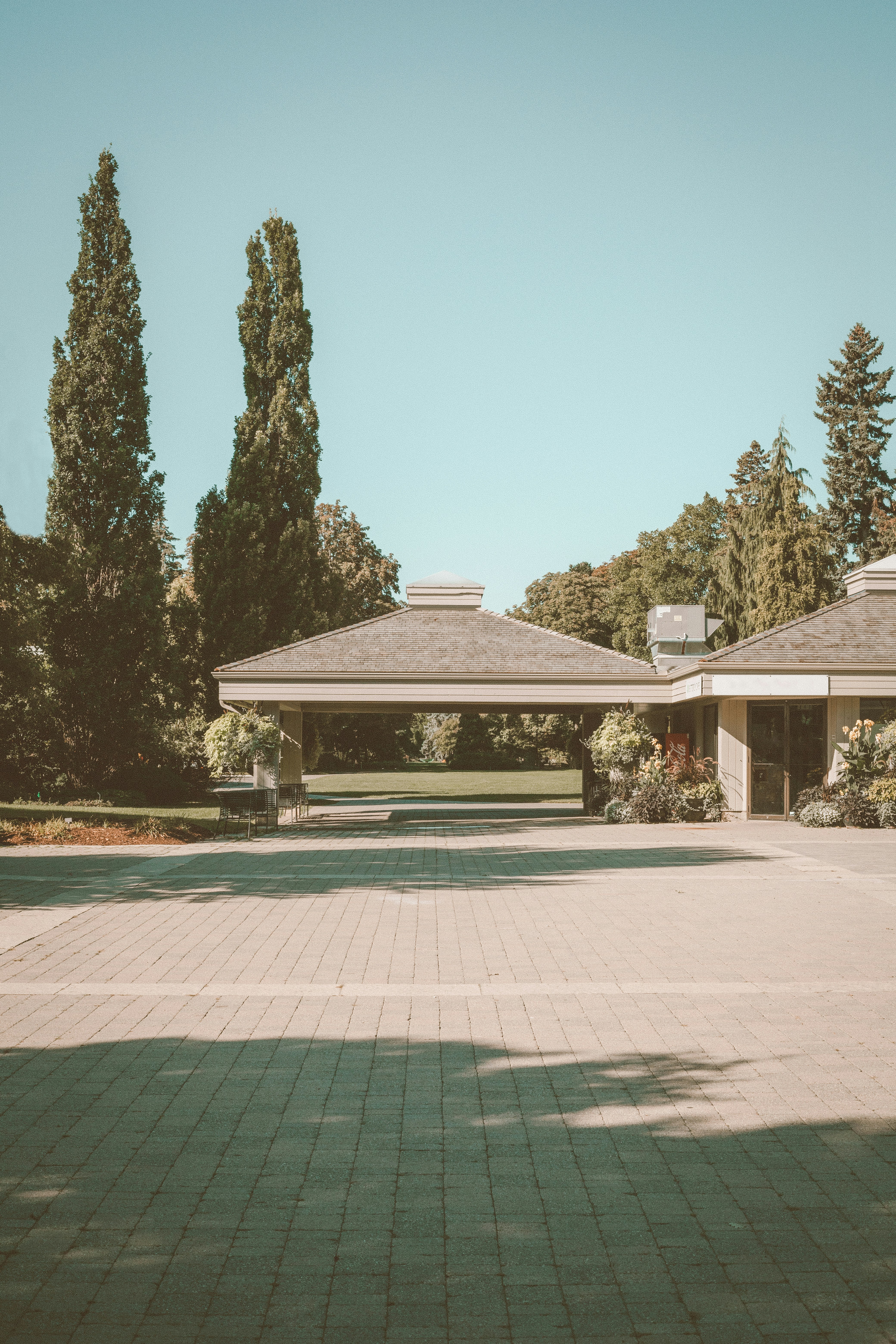 Casa de hormigón blanco y marrón cerca de árboles verdes bajo el cielo azul durante el día