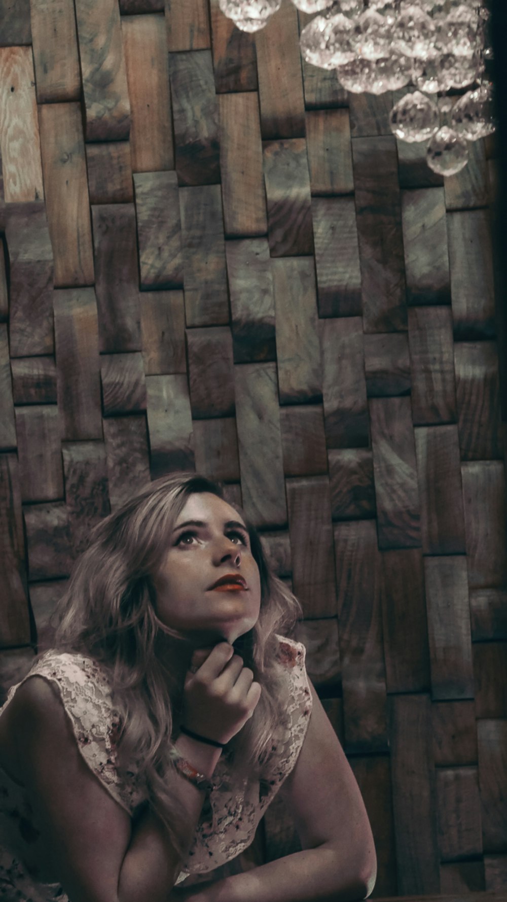 woman in white lace shirt leaning on brown wooden wall