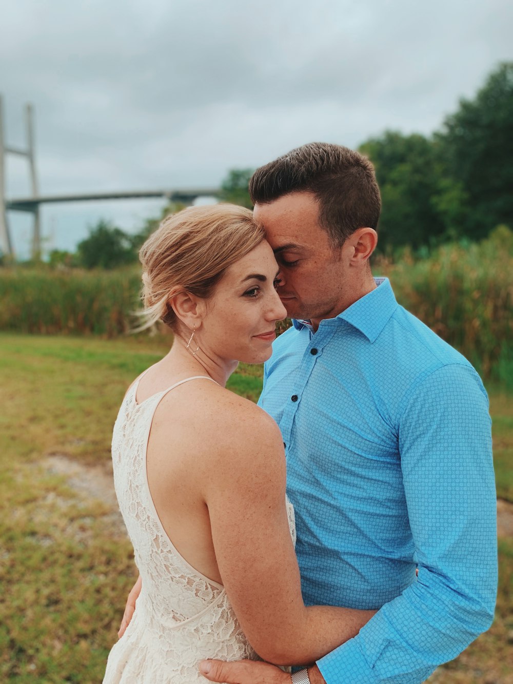 man in blue dress shirt kissing woman in white tank top