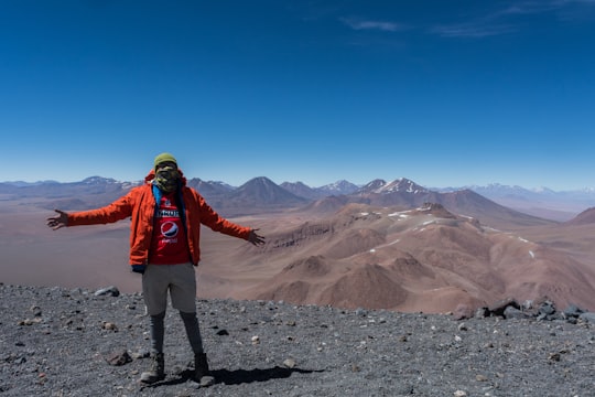 man in blue jacket and brown pants standing on rocky ground during daytime in Antofagasta Chile