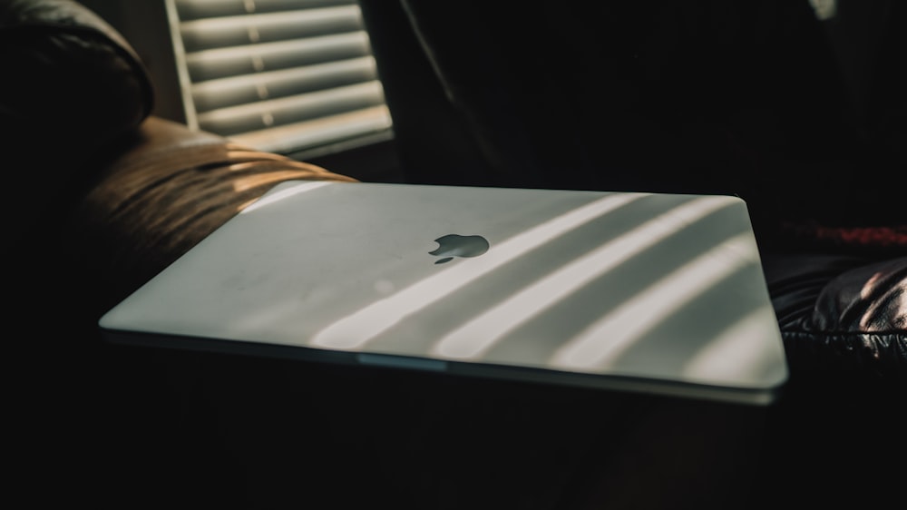 silver macbook on white table