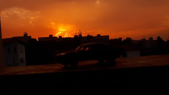 A sleek car silhouette with a 'Coming Soon' banner over a city backdrop at sunset.