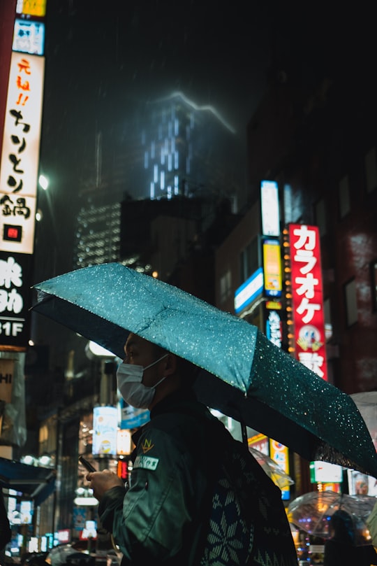 person in black jacket holding umbrella in Shibuya Japan