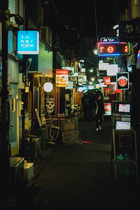 man in black jacket walking on street during nighttime in Shinjuku Japan