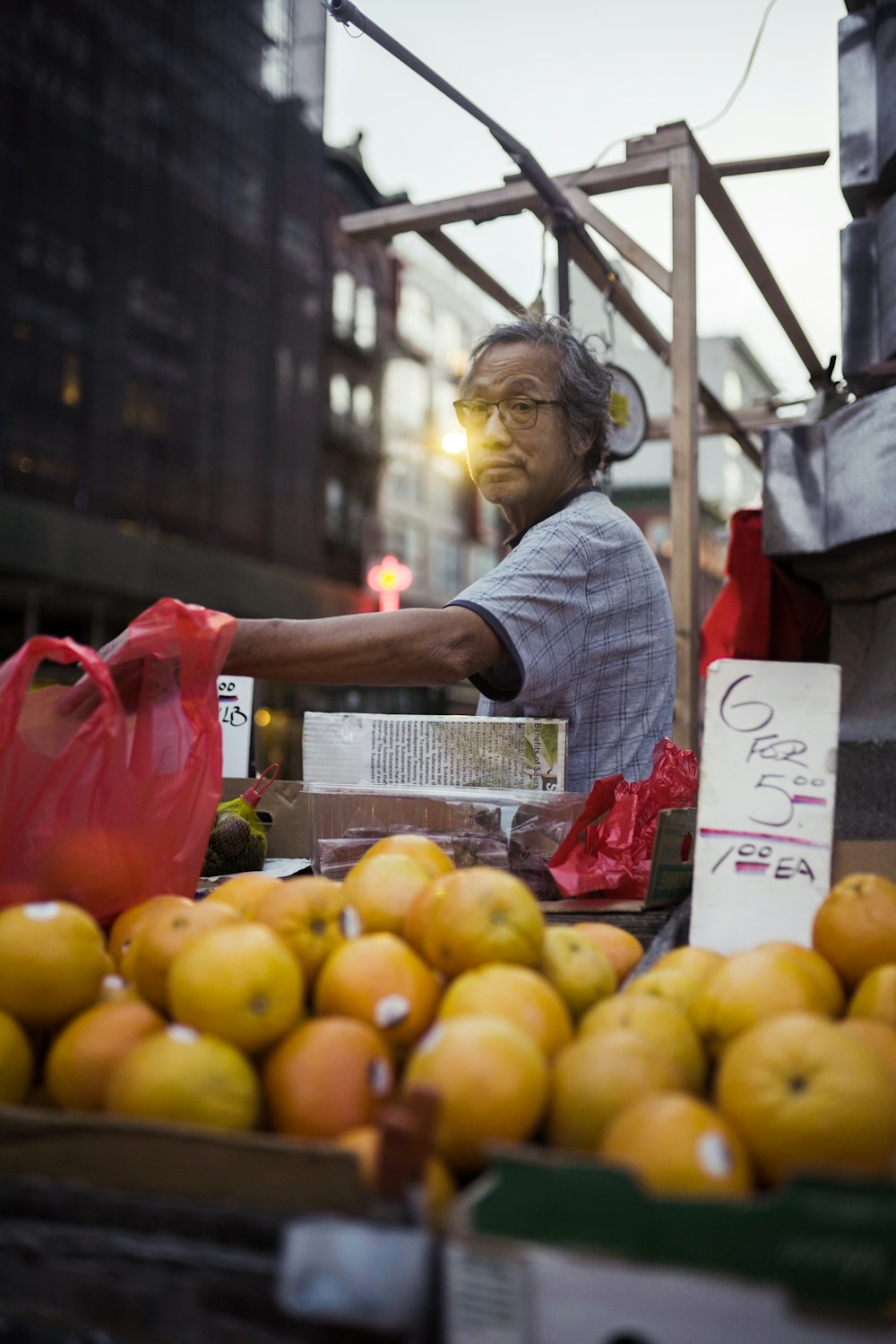 a man standing next to a pile of oranges