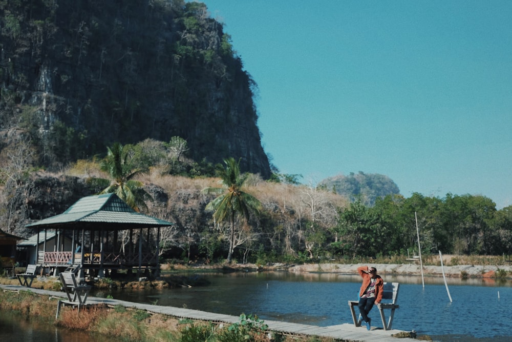 man and woman sitting on bench near body of water during daytime