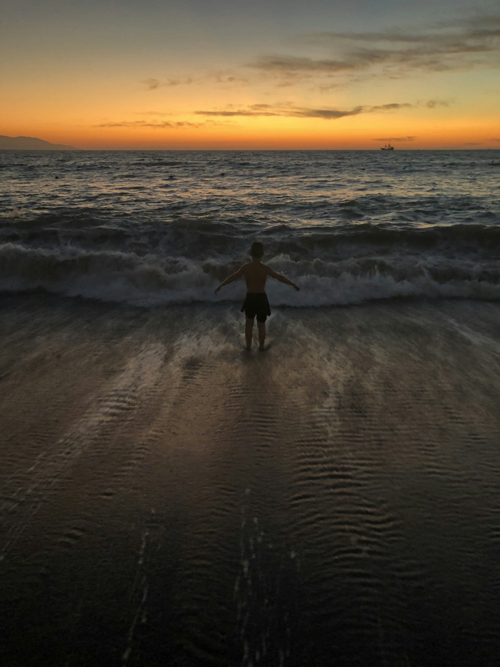 man in black wet suit walking on beach during sunset