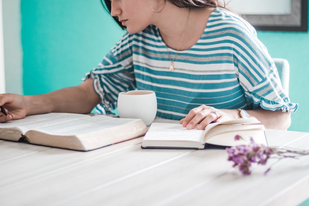 woman in blue and white striped shirt holding white ceramic mug