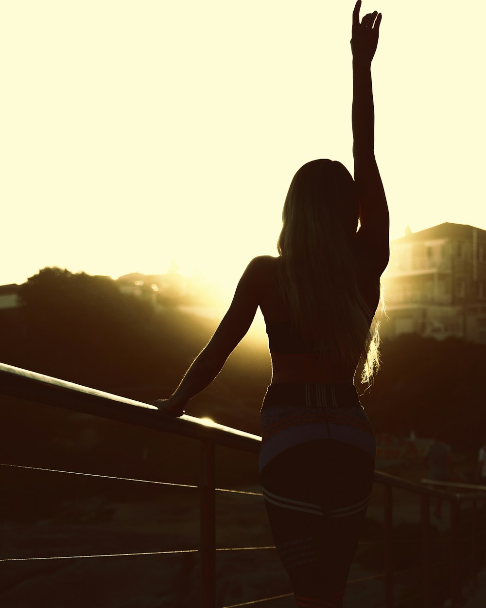 woman in white tank top and black shorts standing on balcony during sunset