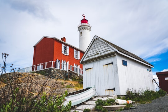 white and red house near green trees under white clouds during daytime in Fisgard Lighthouse National Historic Site Canada