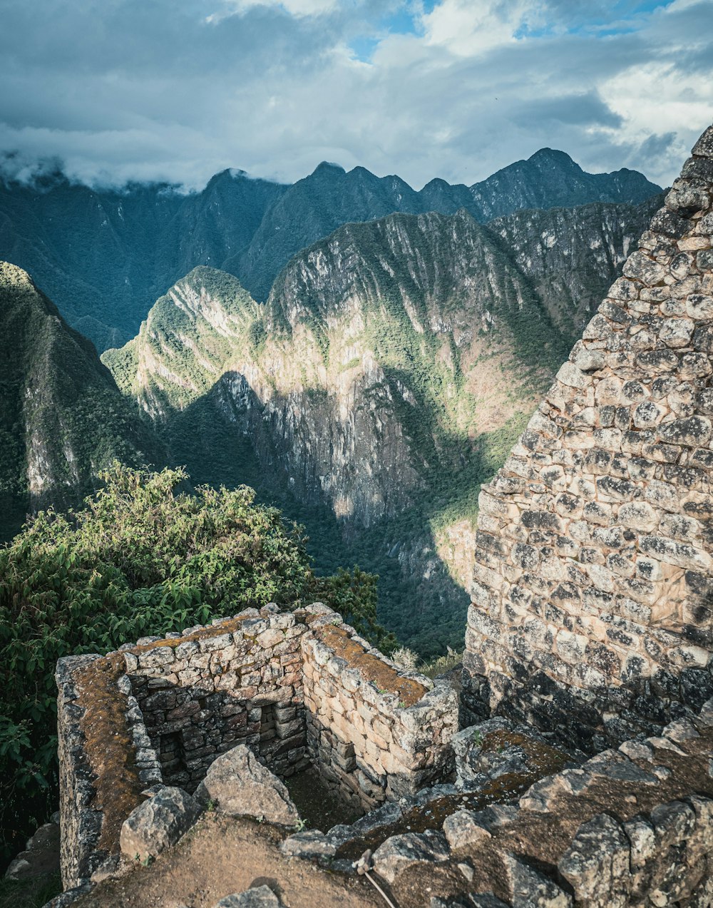 brown brick wall near green trees and mountain during daytime