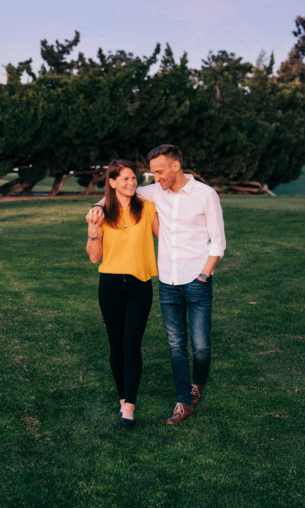 man in white dress shirt and woman in brown long sleeve shirt standing on green grass