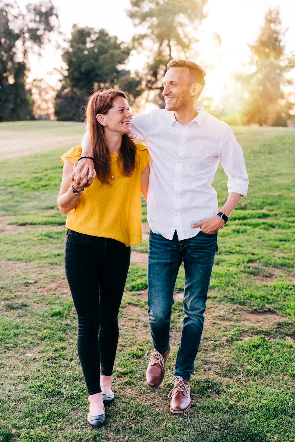 homem na camisa social branca e mulher na camisa laranja de manga comprida em pé na grama verde