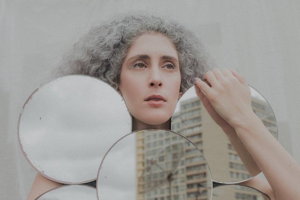 femme tenant un miroir rond blanc