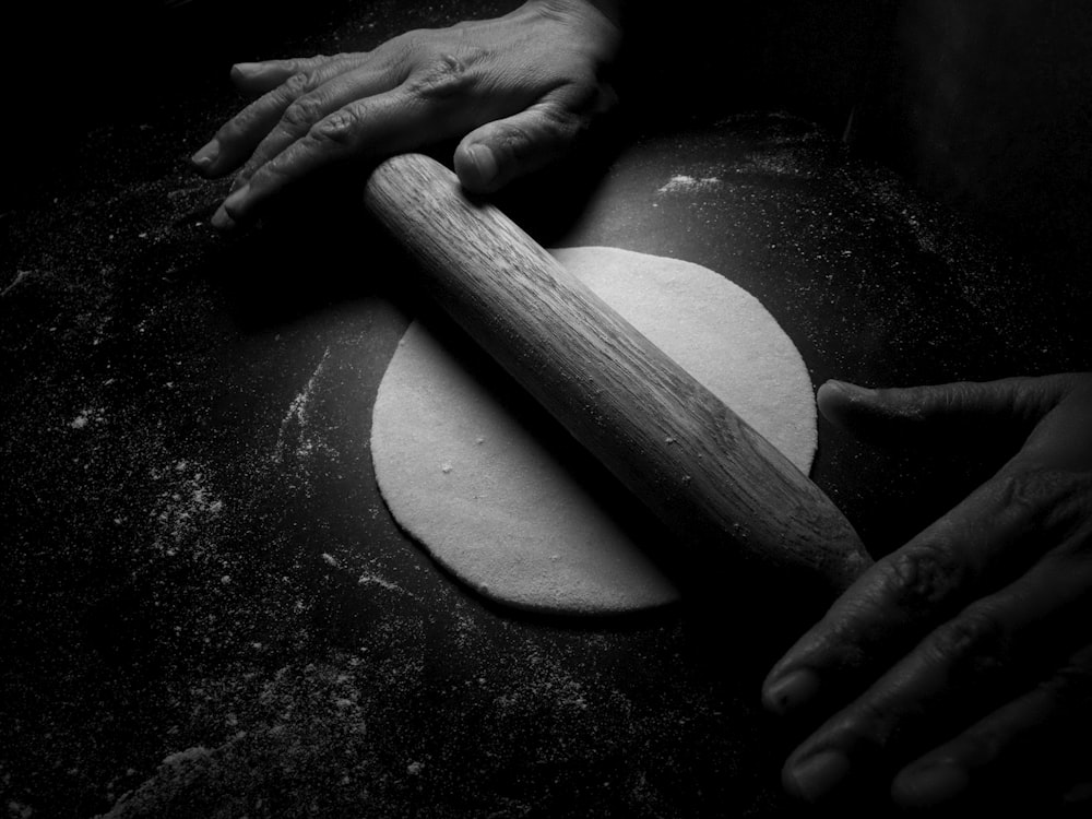 person holding brown wooden rolling pin