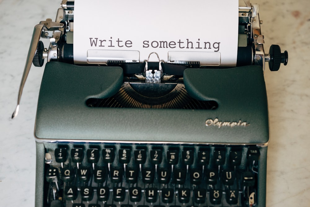máquina de escrever preta e branca na mesa verde